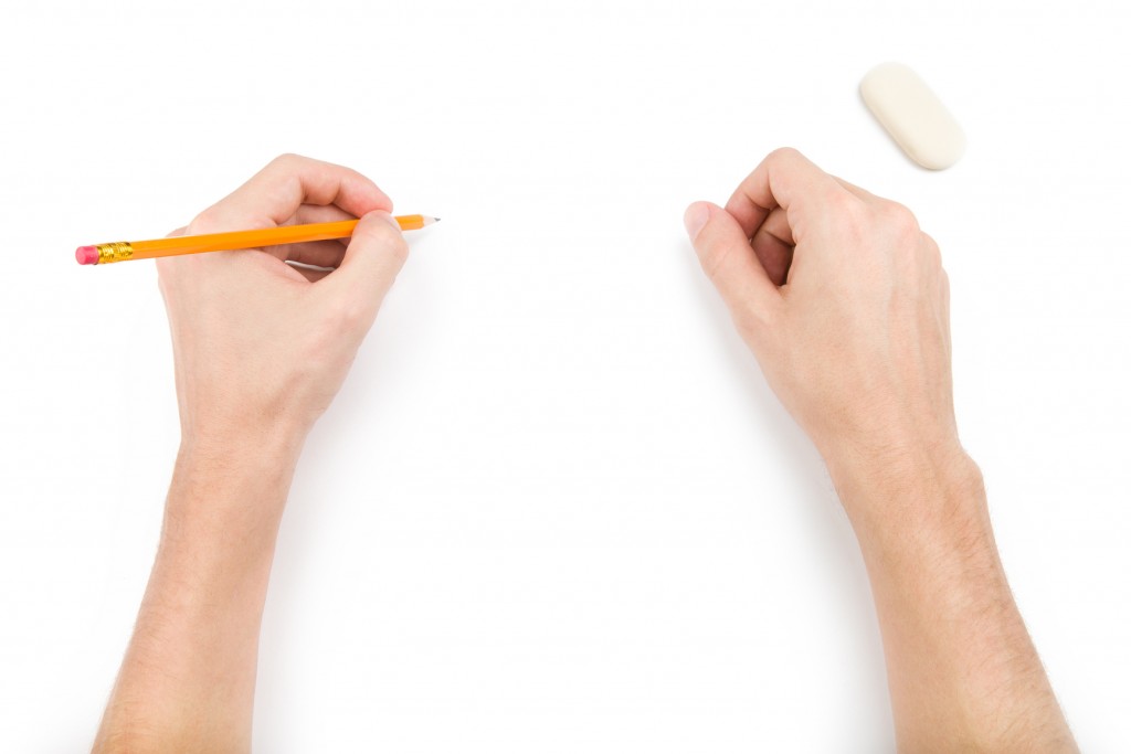 Left-hander with pencil writing something. Isolated on white